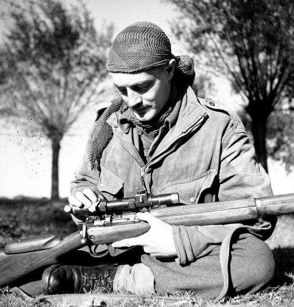 Sergeant H.A. Marshall of The Calgary Highlanders cleans the telescopic sight of his No.4, MkI(T) rifle