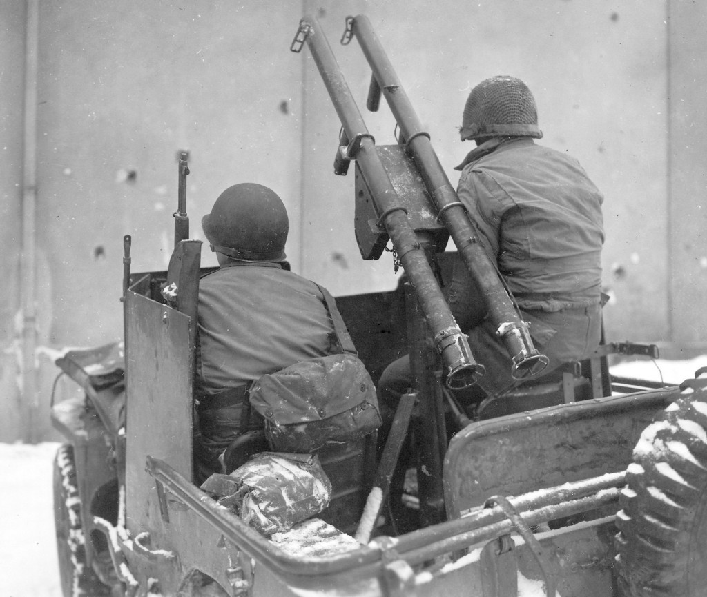US troops in an armored Jeep with a pair of bazookas mounted on the gun pintle